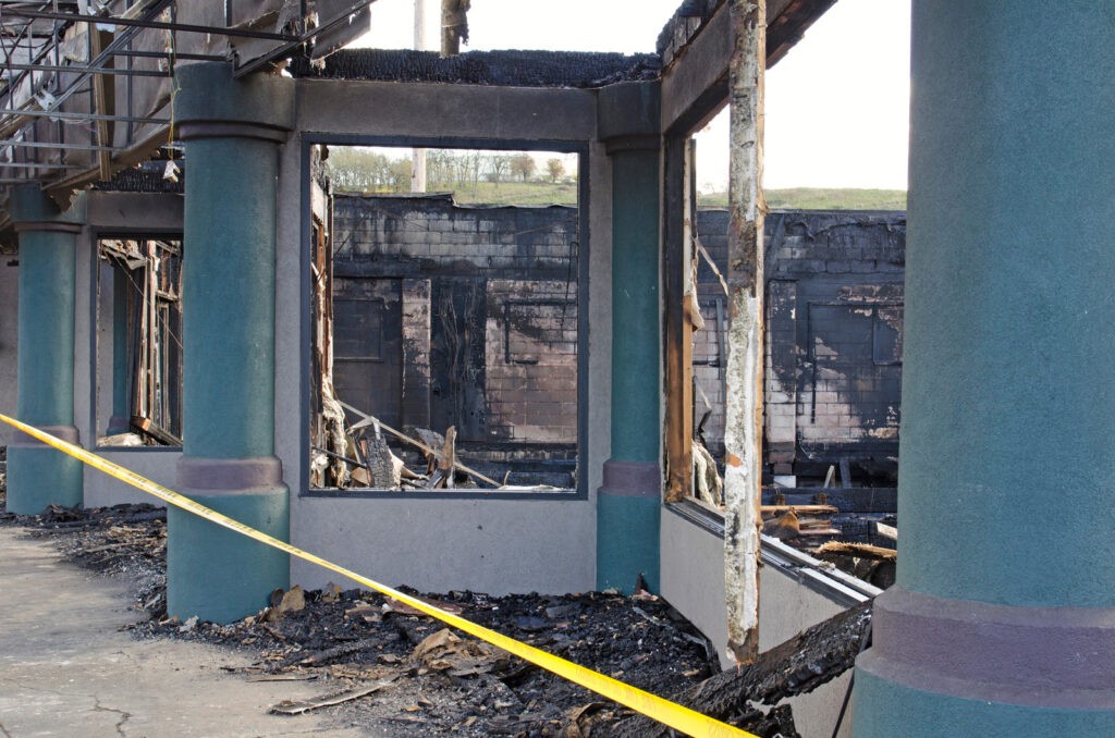 Fire-damaged building interior with charred walls, debris, and exposed structural columns after severe structural fire damage